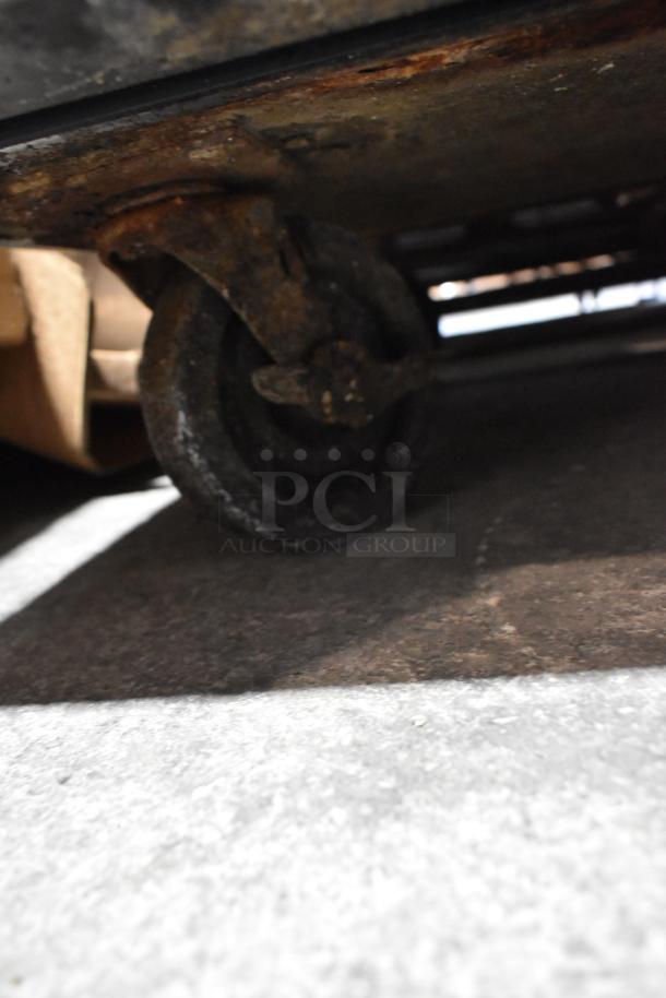 Rusty wheel of True TUC-48 Commercial Cooler on concrete floor, highlighting condition for auction.