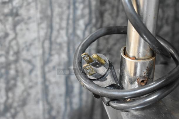 Close-up of a power plug and cord on a stainless steel pole, part of True TUC-48 commercial cooler, showing signs of wear.