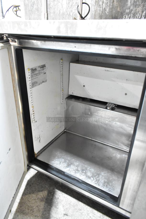 True TUC-48 stainless steel 2-door work top cooler, interior view. Features shelves, model label, on casters. 115V, 1 phase.