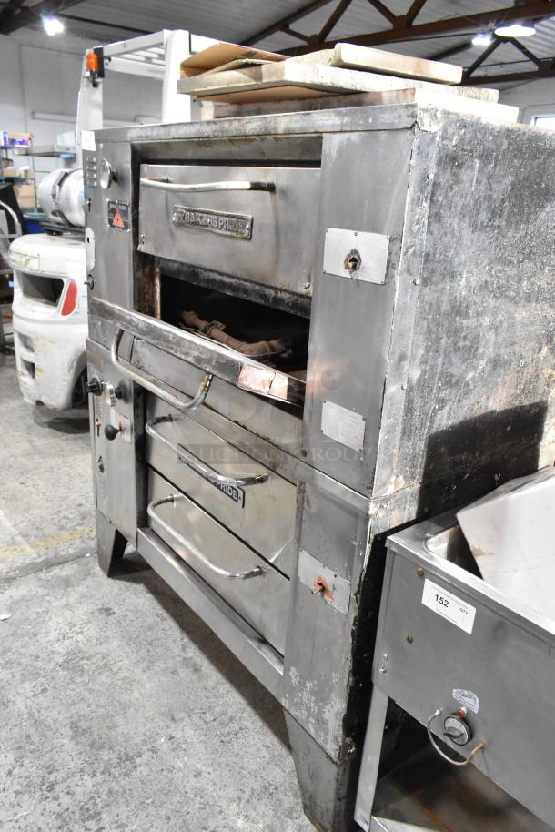 "2 Bakers Pride gas pizza ovens, stainless steel, single deck, includes cooking stones, used condition, branded."