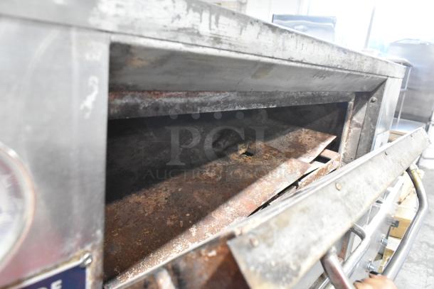 Bakers Pride stainless steel gas-powered single deck pizza oven with cooking stones, some visible rust and wear.