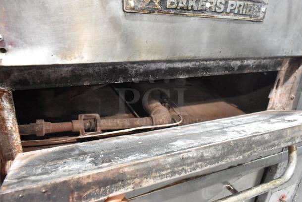 Bakers Pride stainless steel gas-powered single deck pizza oven with cooking stones, worn condition, visible piping.