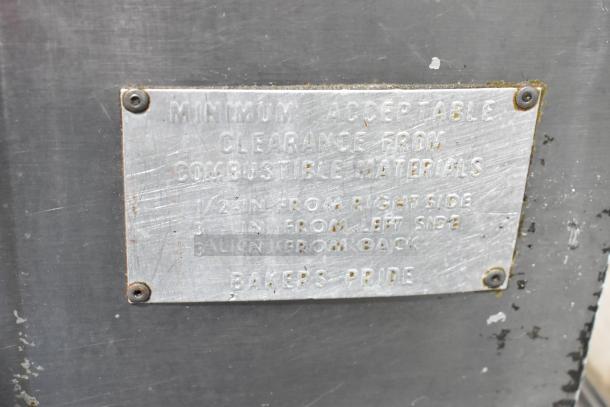 2 Bakers Pride stainless steel gas pizza ovens with cooking stones. Visible clearance warning label. Commercial use.