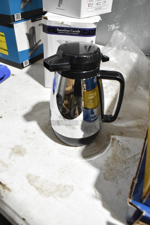 Stainless steel pitcher with black handle and spout, new condition, labeled "Stainless Carafe" on box.