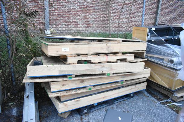 Stack of five various glass doors in wooden crates, stored outdoors, suitable for bidding.