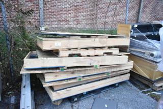 Stack of five various glass doors in wooden crates, stored outdoors, suitable for bidding.