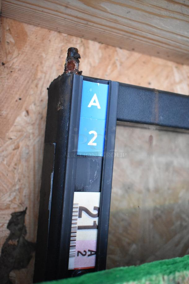 Five various glass doors with black frames, labeled "A2" and "21A2," indicating model or batch. Some rust visible on screws.