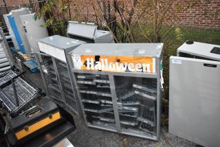 Three gray cabinet merchandisers with glass doors, Halloween decor, used condition, various shelving, labeled with lot numbers.