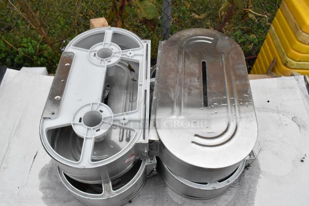 9 stainless steel toilet paper dispensers, some with slight wear, stack on white paper outdoors.