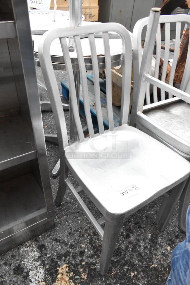 Gray metal dining height chair, pre-owned, with visible wear. Features a slatted back design. Auction label "337" on seat.