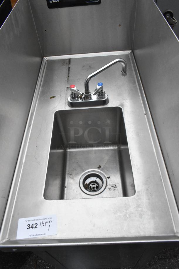 Stainless steel single bay sink with side splash guards, featuring dual-handle faucet. Some surface marks visible.