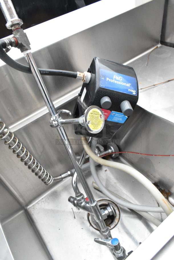 Stainless steel 3 bay sink with dual drain boards, in used condition. Features industrial faucet and P&G Professional device.