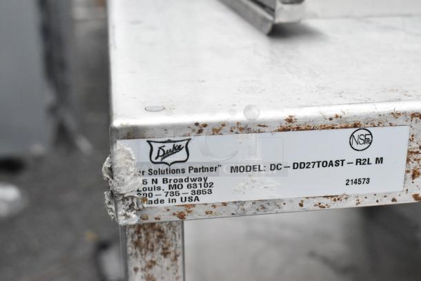 Stainless Steel Commercial Counter with Over Shelf, Model DC-DD27TOAST-R2L M. Features rust spots, NSF certified, made by Duke.