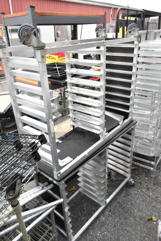 Two metal double pan transport racks with commercial casters, in good condition, ideal for baking or catering.