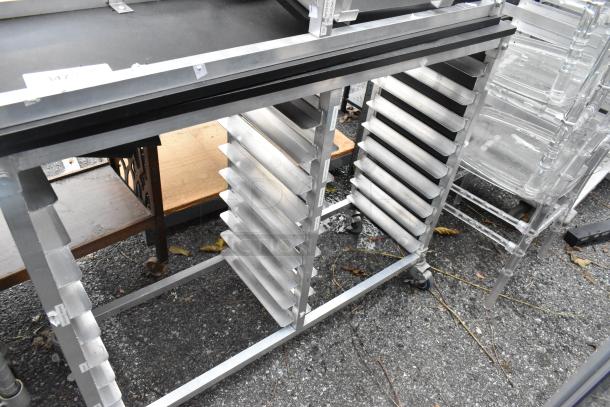 Two metal double pan transport racks on commercial casters, excellent condition. Features multiple pan slots, ideal for catering.