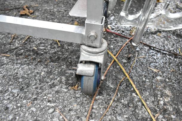 Two metal double pan transport racks with sturdy commercial casters, used condition, ideal for storage and mobility.