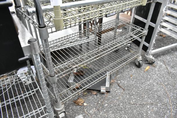 Two metal wire shelving units with four-tier adjustable shelves, on wheels. Includes contents; used condition.
