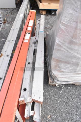 Three various metal ladders, includes extension and step types. Visible wear, labels indicate safety instructions.