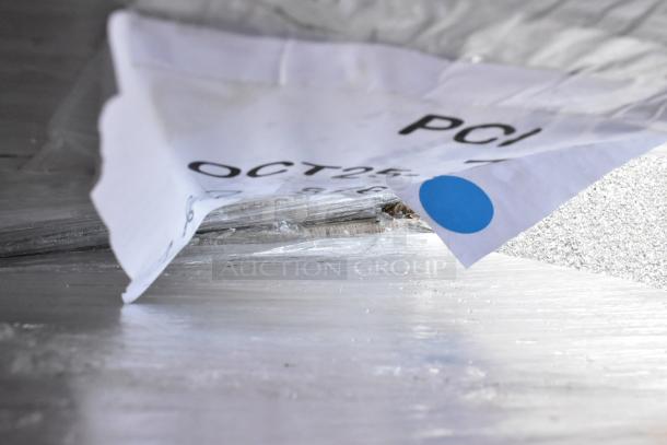 Plastic-wrapped pallet with a label reading "OCT25 PCI," showing auction item packaging for chairs and tables.