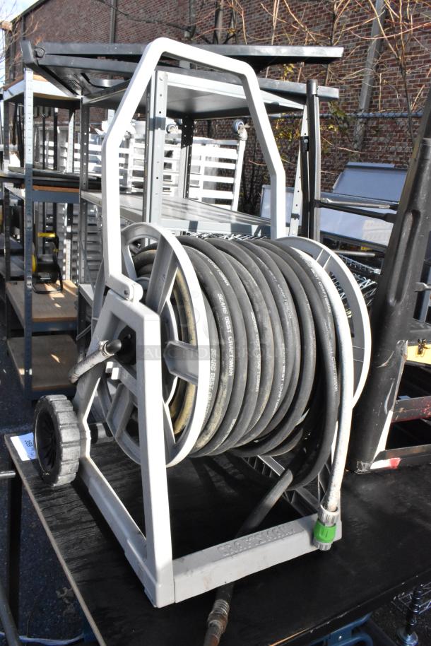 Cart with a mounted hose reel featuring a Craftsman hose, surrounded by metal shelving and folded bar stools. Auction lot.