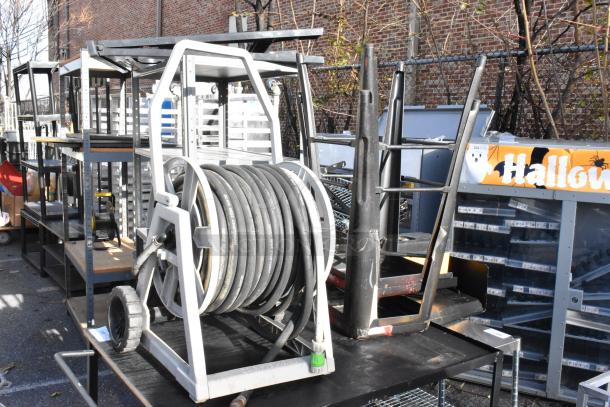 Cart with metal frame holding hose on reel, includes stacked black bar stools. Used condition, ideal for storage or workshop.