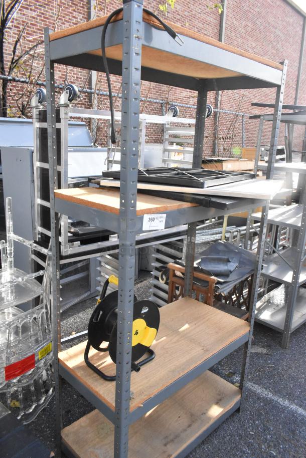 Gray metal shelving unit with wood shelves in fair condition; includes an extension cord reel, measures approximately 6 feet tall.