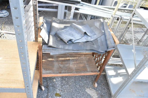 Three-item lot featuring a gray metal shelving unit, wooden two-tier cart on casters, and another gray metal shelving unit.