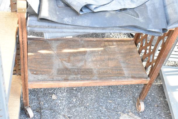 Gray metal shelving unit and wooden two-tier cart on casters, used condition, with visible dust and wear.