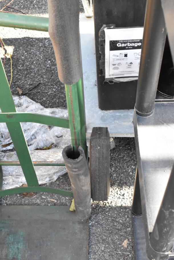 Green metal furniture dolly with padded handles and black wheels, shown in outdoor setting. Some wear visible.