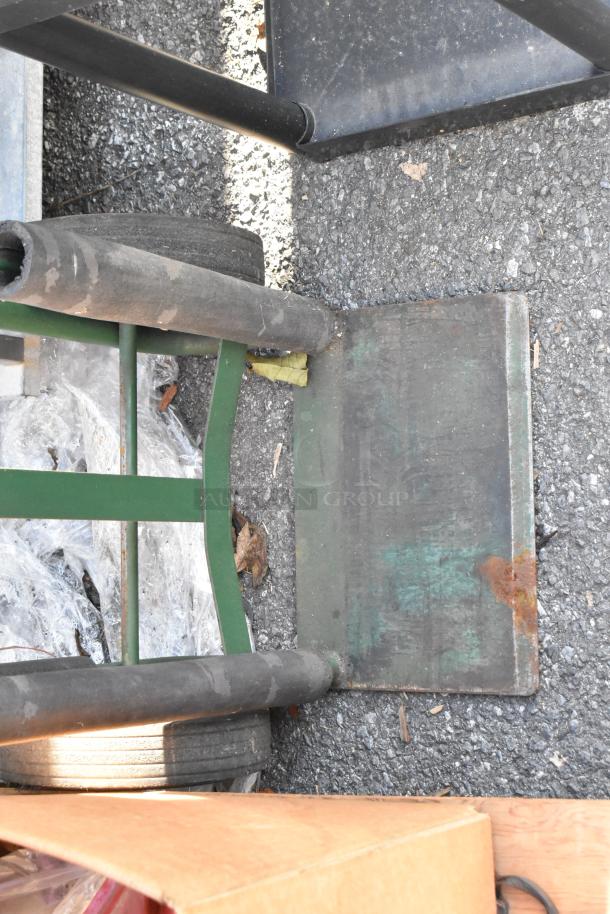 Green metal furniture dolly with rubber wheels and rust on the platform, suitable for moving heavy items.