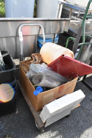 Flat cart with mixed contents, including box, tubing, straps, and more; fair condition with visible tags and markings.