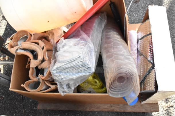 Flat cart containing various items including leather tools, rolled plastic sheeting, metal brackets, and insulation material.
