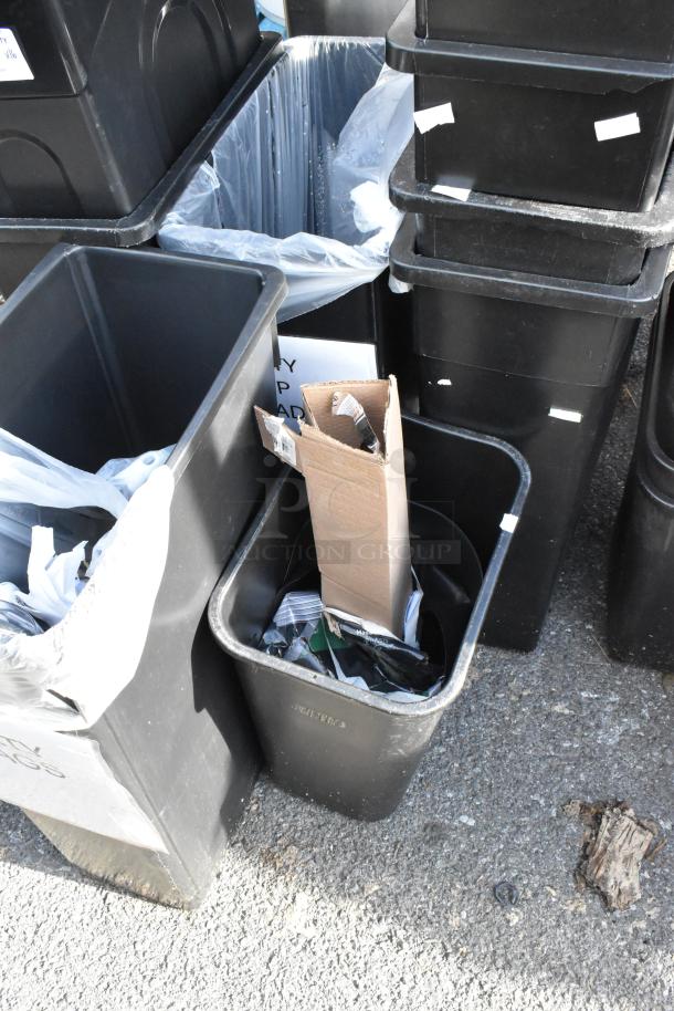 16 large black poly trash cans, used condition, stacked. Some cans hold cardboard and plastic liners. Auction lot of 16.