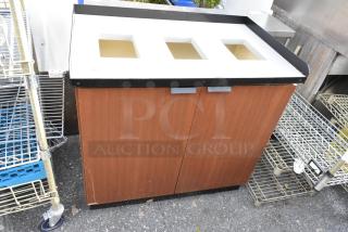 Wood-patterned trash can shell with three deposit holes and two front doors, showing mild wear.