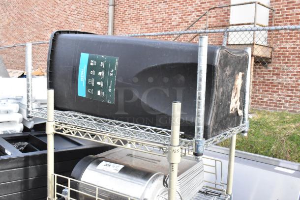 Wire shelving unit on commercial casters with contents, including a black trash can. Buyer must dismantle.