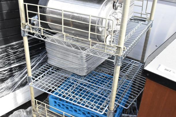Wire shelving unit on casters with contents including metal trays and a trash can. Buyer must dismantle. Consider freight.