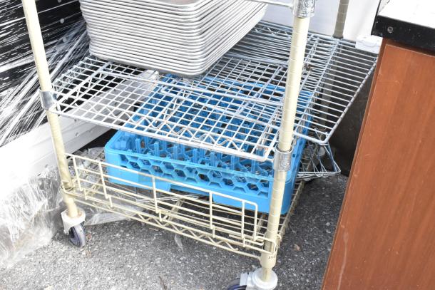 Wire shelving unit on commercial casters with trays and plastic bin. Needs dismantling. Check freight charges.