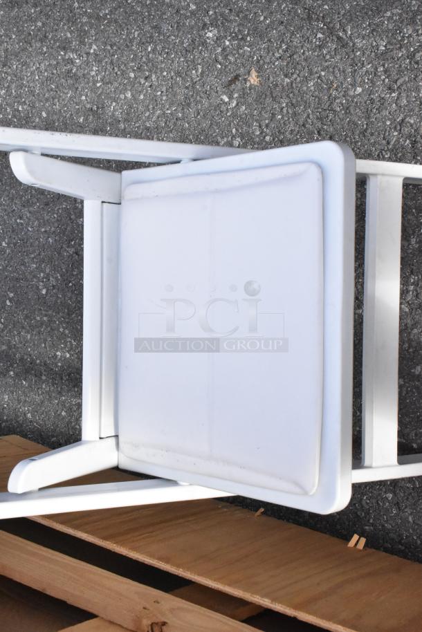 White folding chair with a black frame on a wooden platform. Durable, suitable for events. Set of 56 available.