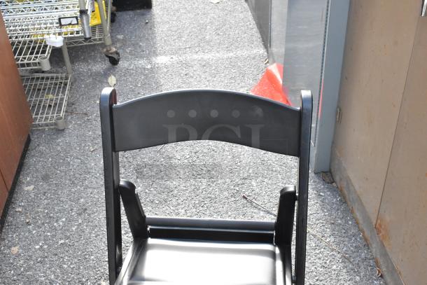 Black folding chair, part of 56-chair auction set. Features a sturdy frame and seat, ideal for events.