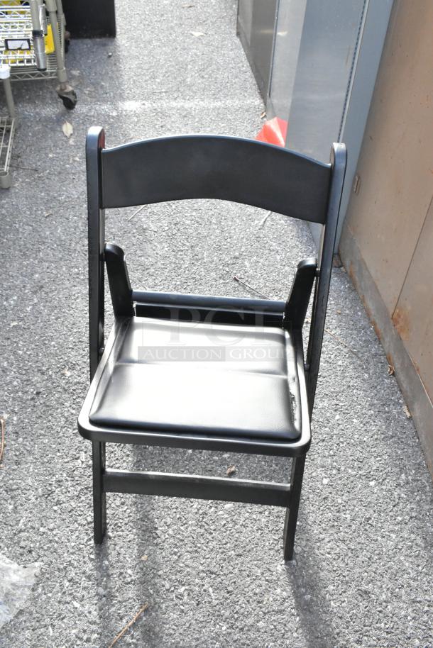 White and black folding chair, sleek design, metal frame, slightly used. Comfortable cushioned seat, stackable for storage.
