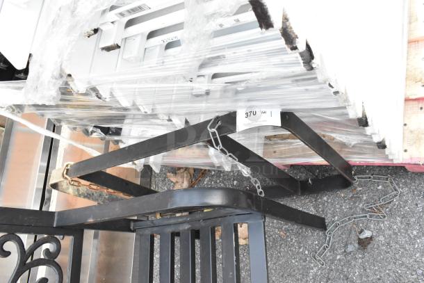 Black metal pot rack, robust construction, features attachable chains for hanging. Condition appears lightly used. Auction label visible.