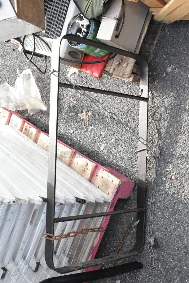 Black metal pot rack with chain attachments, rectangular frame, used condition. Ideal for kitchen organization.