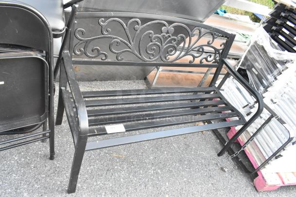 Black metal bench with armrests, featuring ornate back detailing. Shows a label with number 374. Condition: good, slight wear.