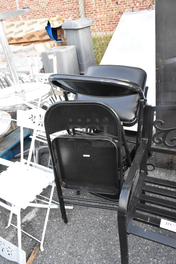 Assorted furniture items including black folding chairs and white tables, pre-owned condition, outdoor setting.