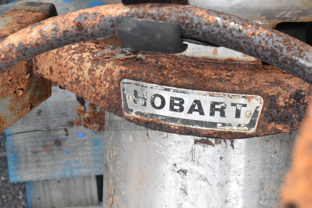 Rusted Hobart Cutter Mixer with visible brand label, showing significant wear and oxidation, on a wooden pallet.