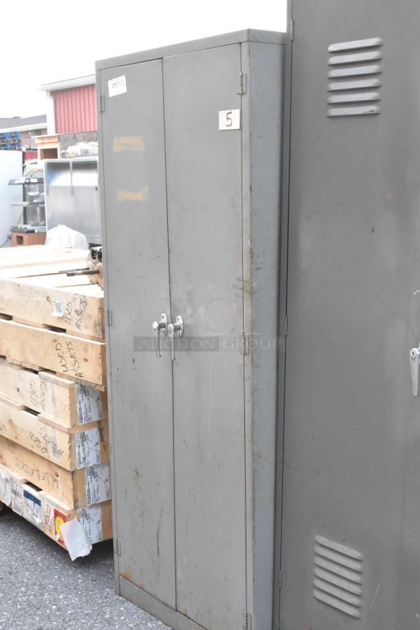 Two metal cabinets with double doors and ventilation slits. Some wear and rust visible. Tag reads "5."