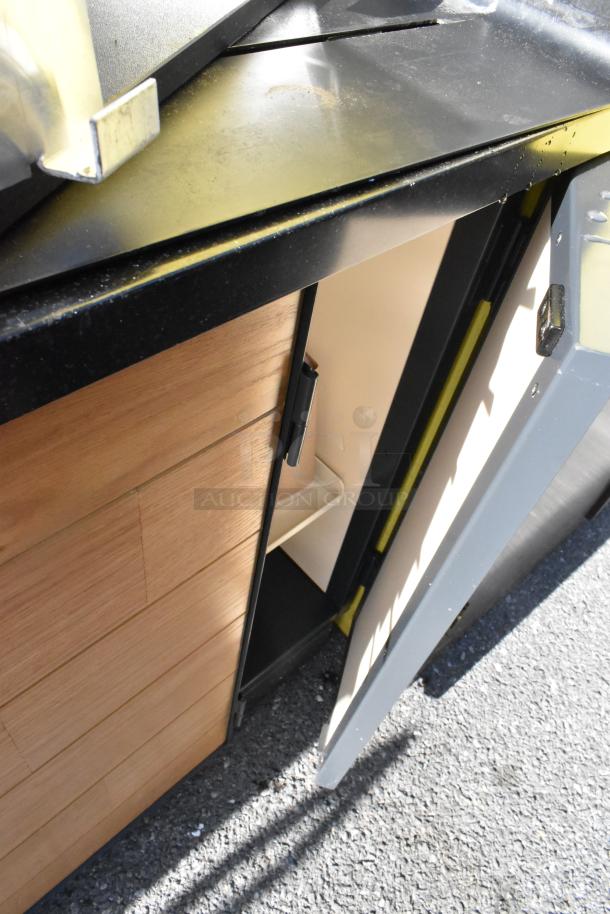 Wooden counter with four doors, featuring a black countertop. Includes interior shelving. Good condition with visible light wear.