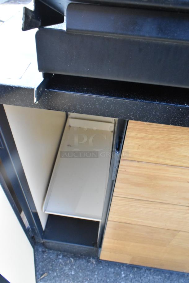 Wooden counter with four doors shown partially open, revealing shelves. Features light wood finish with black accents.