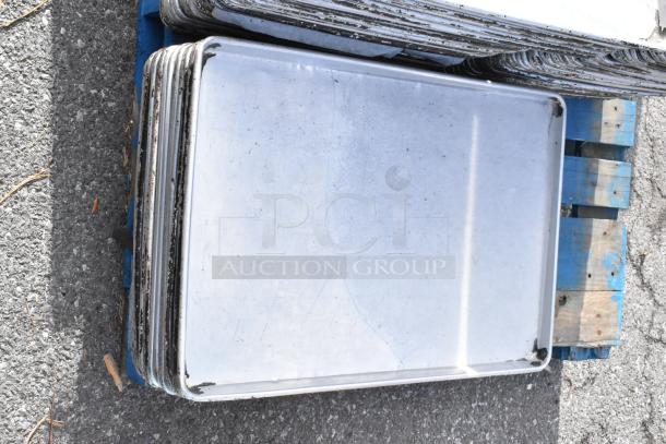 103 full-size metal baking pans stacked on a blue pallet. Some wear visible. Auction item, 103 times your bid.
