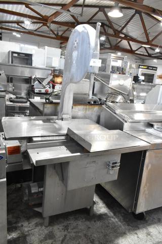 Metal commercial floor-style meat saw, industrial-grade, robust construction, visible wear on table and frame, electric motor.